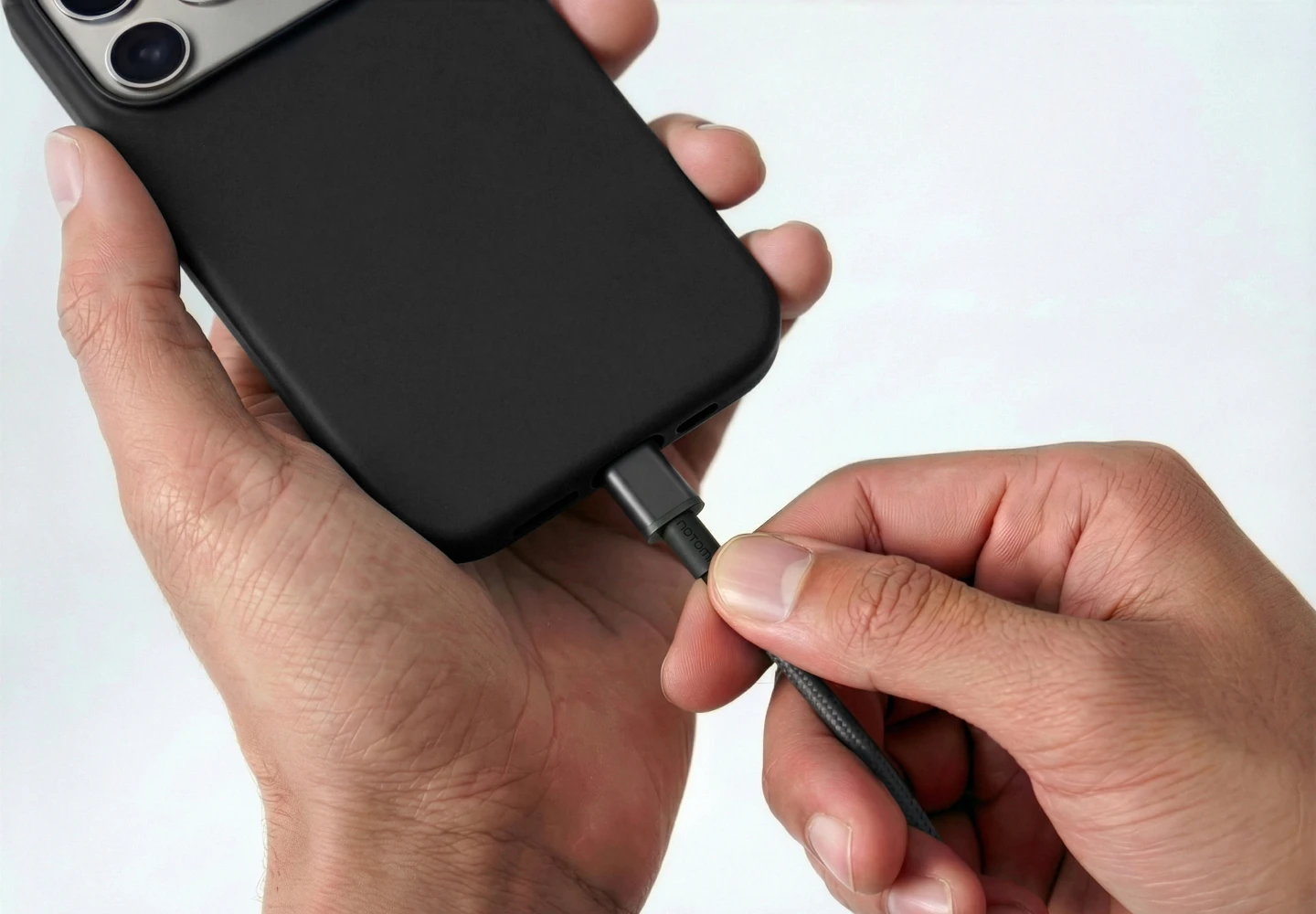 Dłonie podłączają smartfon do ładowania białym kablem magnetycznym USB-C do USB-C Notomi 100 W, prezentując dopasowanie wtyku do otworu w etui.