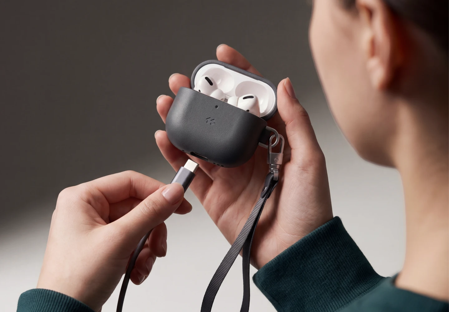 Kobieta podłącza kabel USB-C do pomarańczowego etui Notomi ze skóry naturalnej na słuchawki AirPods 5 / 4.