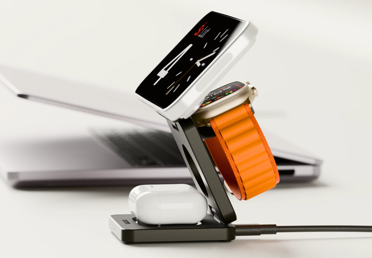 Czarna, składana ładowarka indukcyjna 15 W Noto Charge Pad Go ładuje iPhone’a, Apple Watch i AirPods na biurku obok laptopa.