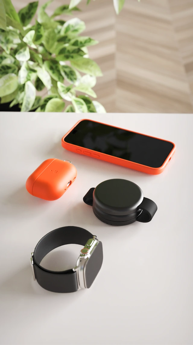Składana biała mini ładowarka indukcyjna Noto Charge Pad Go pokazana na stole w formie złożonej, obok Apple Watch, Air Pods Pro 3 i iPhone 17 Pro.