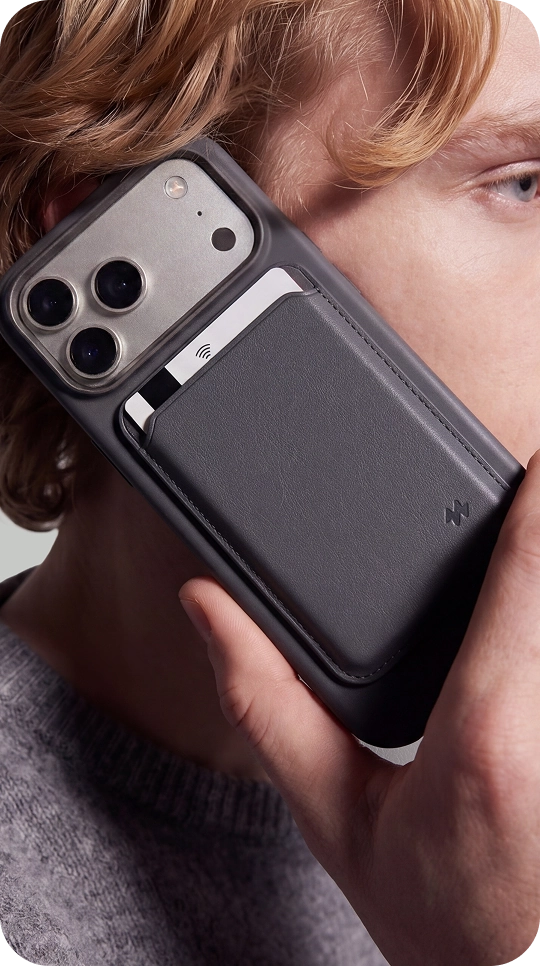 Mężczyzna trzyma smartfon z pomarańczowym magnetycznym portfelem MagSafe Notomi, prezentując eleganckie wykończenie ze skóry wegańskiej i praktyczne miejsce na karty.
