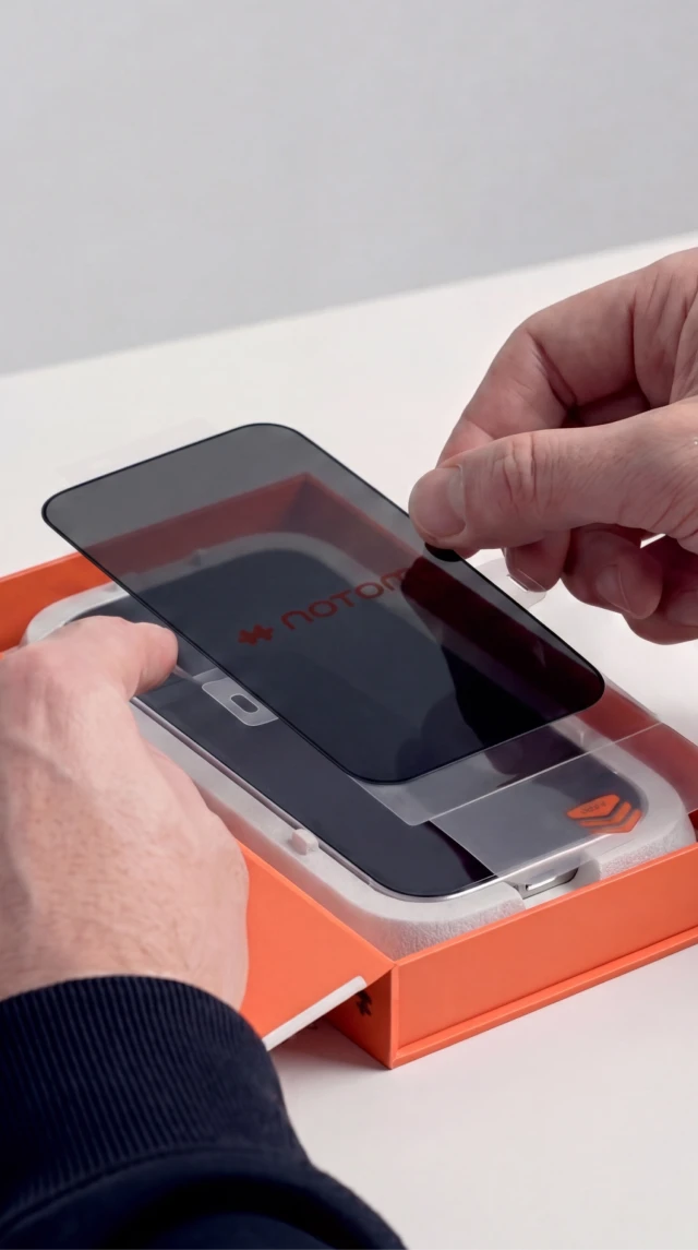 Dłonie montują prywatyzujące szkło hartowane Notomi 9H na iPhone 18 Pro Max z ekologicznym, papierowym aplikatorem.